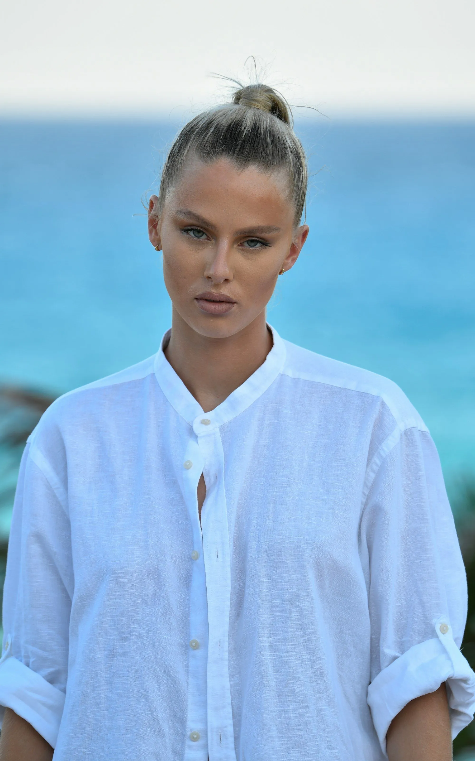 Woman in a white linen shirt by the ocean
